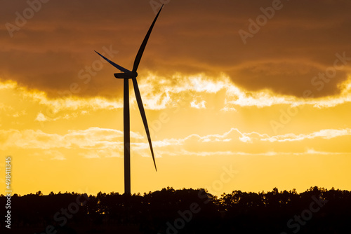 A wind turbine silhouetted against a golden sunset sky photo