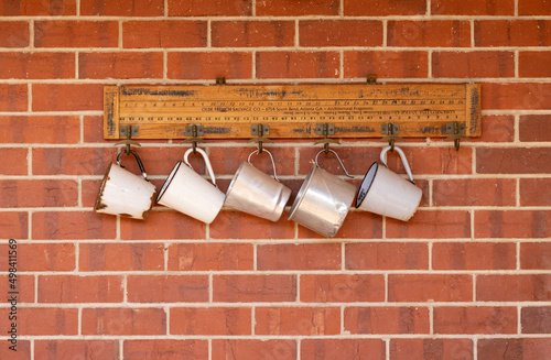 white and silver tin mugs hanging on red brick wall