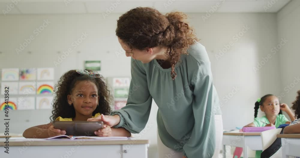 Video of happy caucasian female teacher explaining lesson to african american girl holding tablet Video of happy caucasian female teacher explaining lesson to african american girl holding tablet