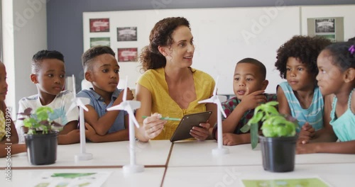 Video of happy caucasian female teacher and class of diverse pupils studying ecology in classroom