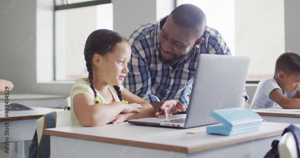 Video of happy african american male teacher helping caucasian girl with laptop Video of happy african american male teacher helping caucasian girl with laptop