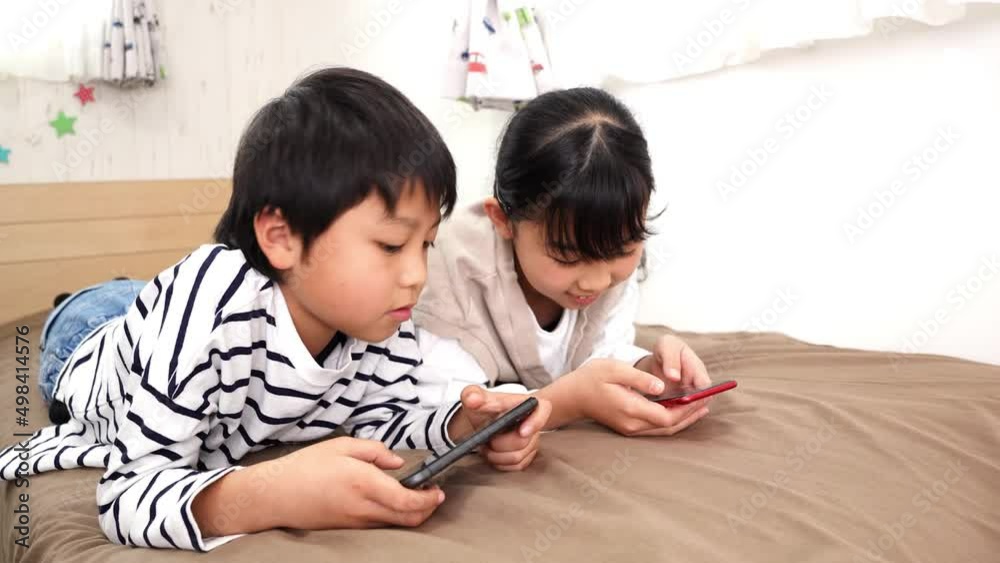 子供部屋でスマホを見ているアジア人の子供 子供部屋でスマホを見ているアジア人の子供