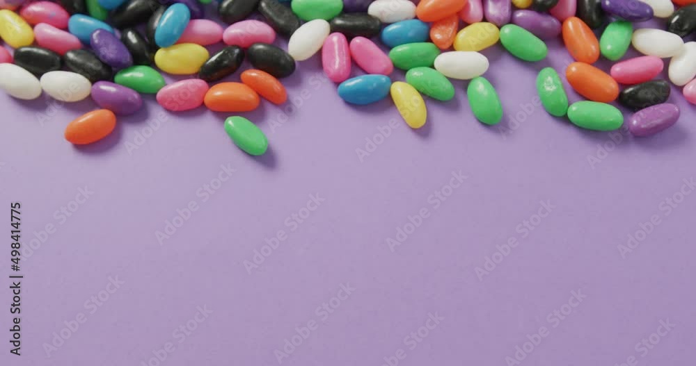 Video of close up of multi coloured sweets with copy space over purple background Video of close up of multi coloured sweets with copy space over purple background