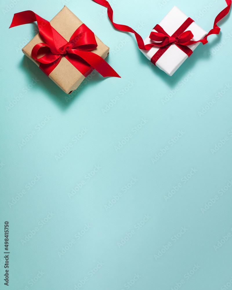 Two white brown paper gift boxes with a red satin ribbon bow and happy birthday sign on top on blue background. Christmas holiday mother and father Valentines days flat lay concept with copy space