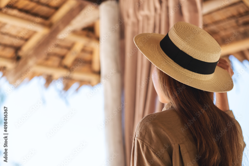 Rear view image of a beautiful young asian woman with hat looking at the beach