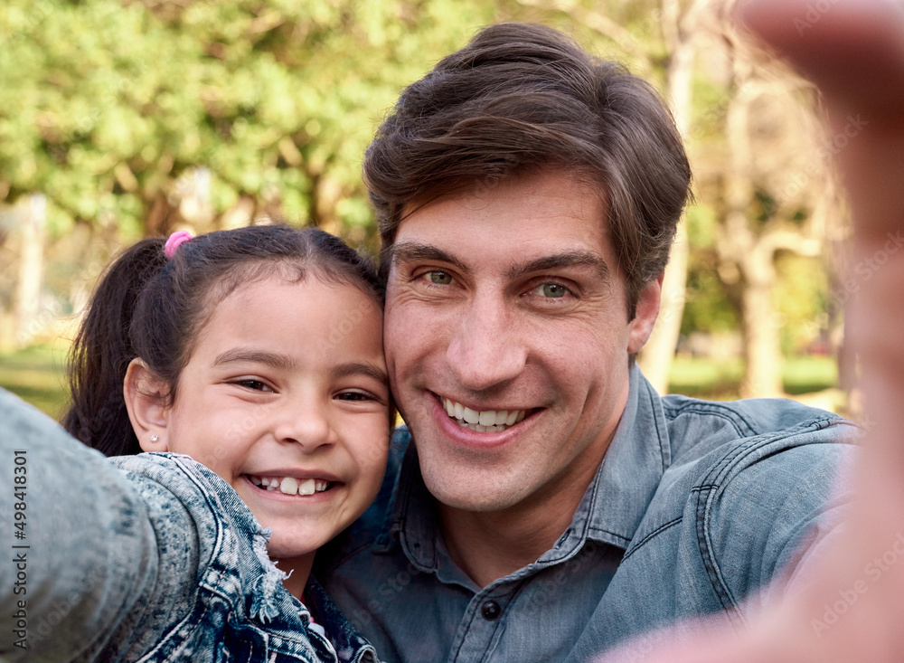 Never forget a single moment. Shot of a happy young man taking a selfie with his adorable daughter in the park. Never forget a single moment. Shot of a happy young man taking a selfie with his adorable daughter in the park.