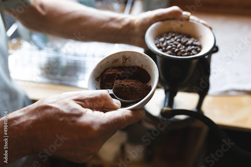 Midsection of caucasian mature man preparing coffee in kitchen at cob house