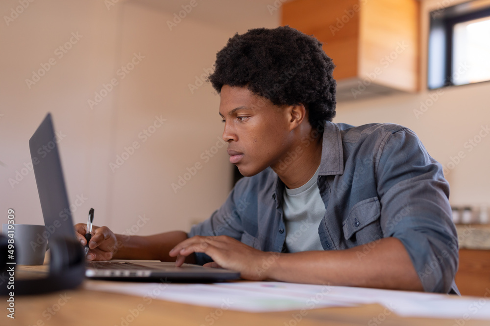African american young businessman using laptop while working at home African american young businessman using laptop while working at home