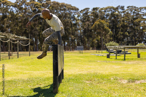 Male african american soldier climbing wooden wall during obstacle course at boot camp photo