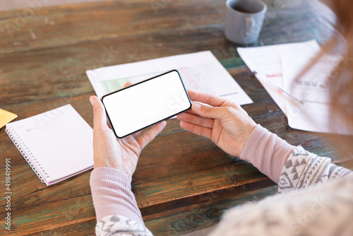 Mid section of caucasian pregnant woman holding a smartphone with copy space while working from home photo