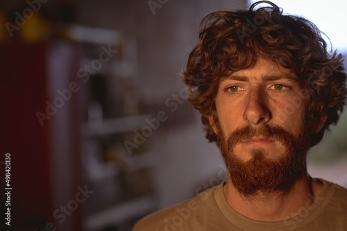 Thoughtful bearded caucasian blacksmith looking away in metal manufacturing industry photo