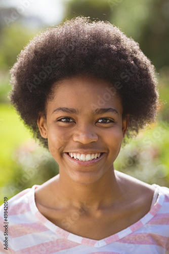 Portrait of happy teenage girl with afro hairstyle in backyard on sunny day photo