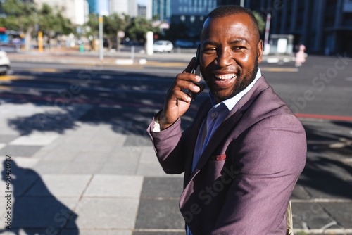 African american businessman talking on smartphone on the street on the go to office photo