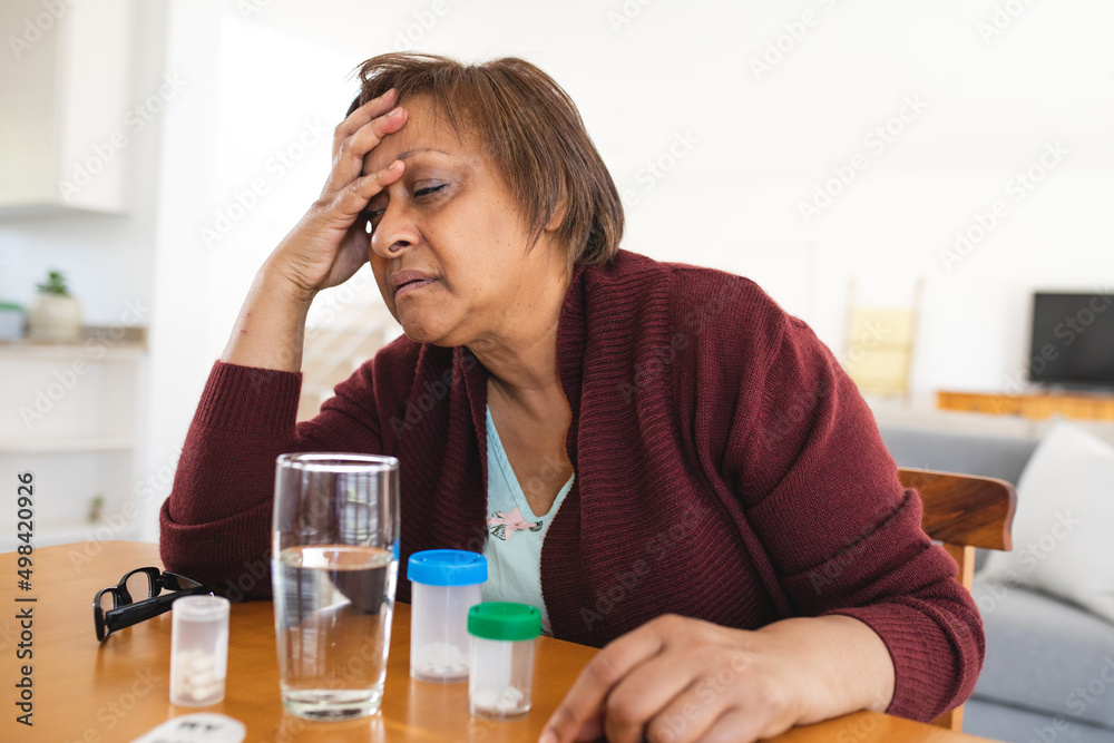 African american senior woman suffering from headache while sitting at table African american senior woman suffering from headache while sitting at table