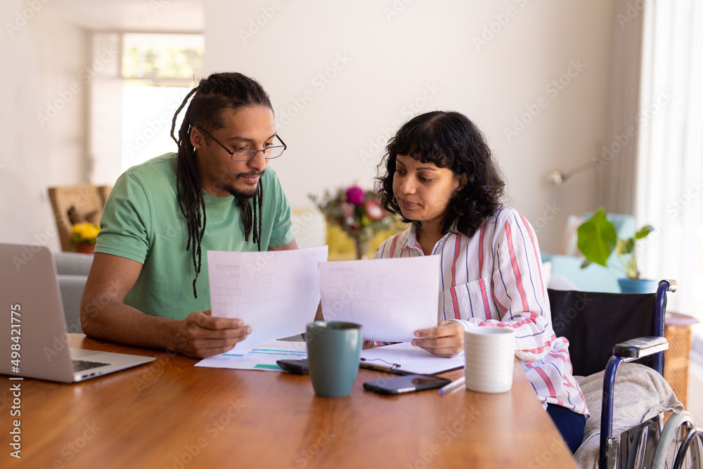 African american disabled woman and her husband calculating finances together at home African american disabled woman and her husband calculating finances together at home
