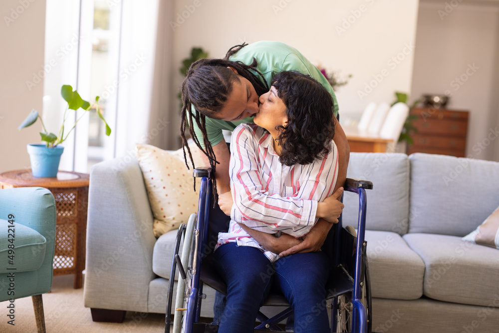 African american man hugging and kissing his disabled wife on wheelchair at home African american man hugging and kissing his disabled wife on wheelchair at home