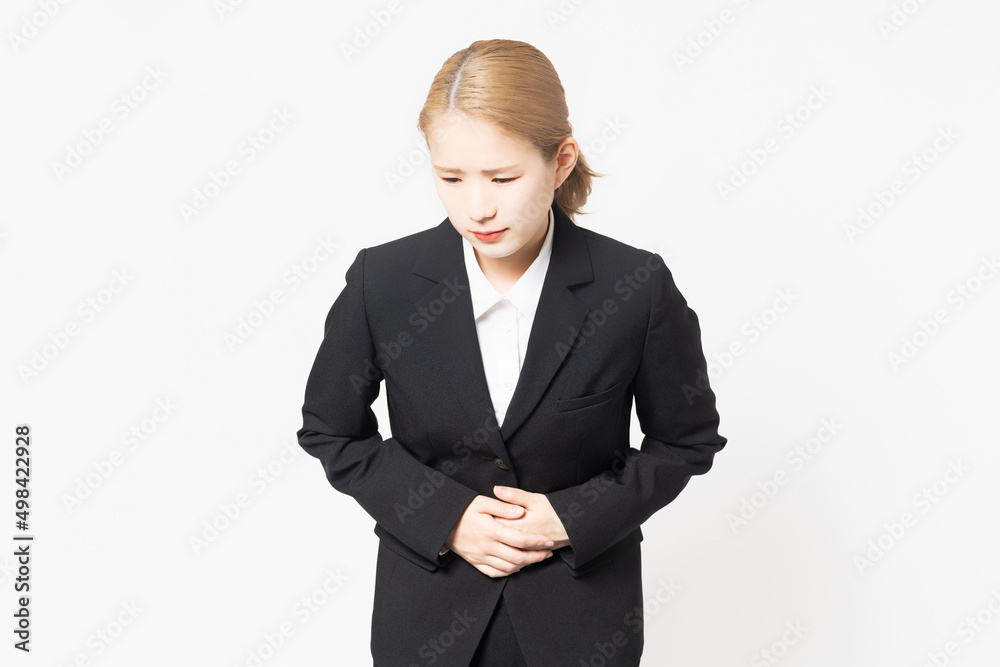 お腹に手を当てるジャケットを着た女性 お腹に手を当てるジャケットを着た女性