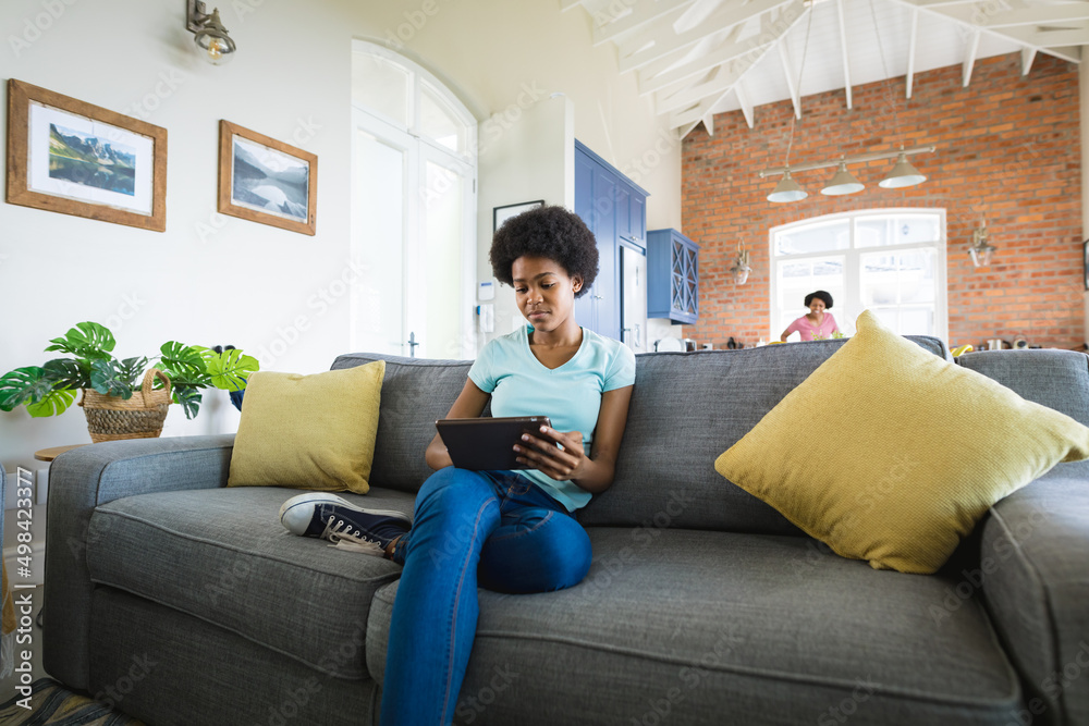 Teenage girl using digital tablet while sitting on sofa in living room at home Teenage girl using digital tablet while sitting on sofa in living room at home