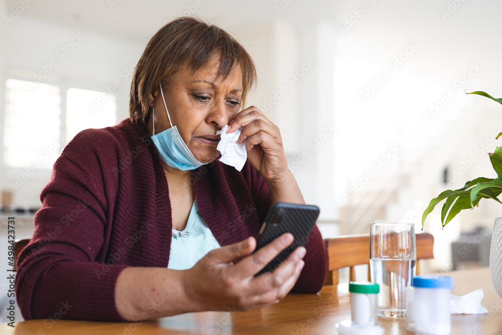 Senior woman in face mask taking online doctor consultation on smart phone while suffering from cold Senior woman in face mask taking online doctor consultation on smart phone while suffering from cold