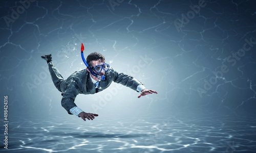 Young businessman in suit swimming