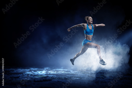 Young beautiful girl doing exercise against dark background © Sergey Nivens