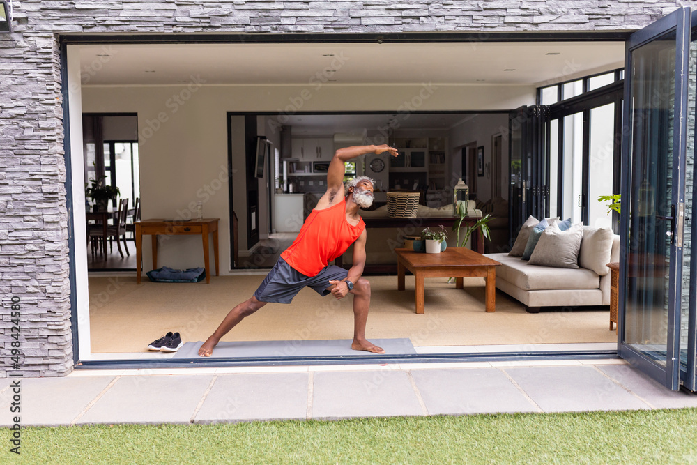 African american senior man practicing yoga on doorway at home African american senior man practicing yoga on doorway at home