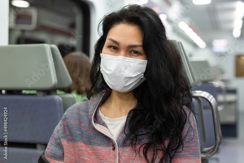 Portrait of young adult relaxed woman wearing face mask for prevent illness using urban train to commute