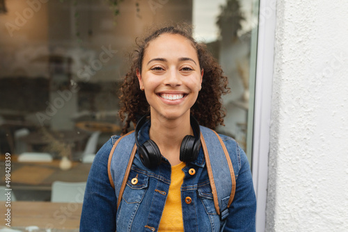 Portrait of smiling young african american woman with wireless headphones in city photo