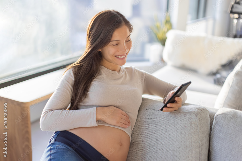 Pregnant Asian woman happy using mobile phone app for shopping or telemedicine. Pregnancy lifestyle at home Pregnant Asian woman happy using mobile phone app for shopping or telemedicine. Pregnancy lifestyle at home