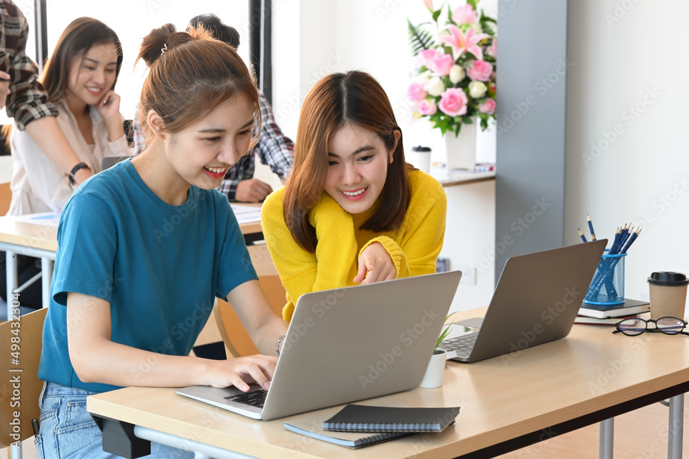 Two cheerful creative women discussing new project plan together in modern office. Two cheerful creative women discussing new project plan together in modern office.