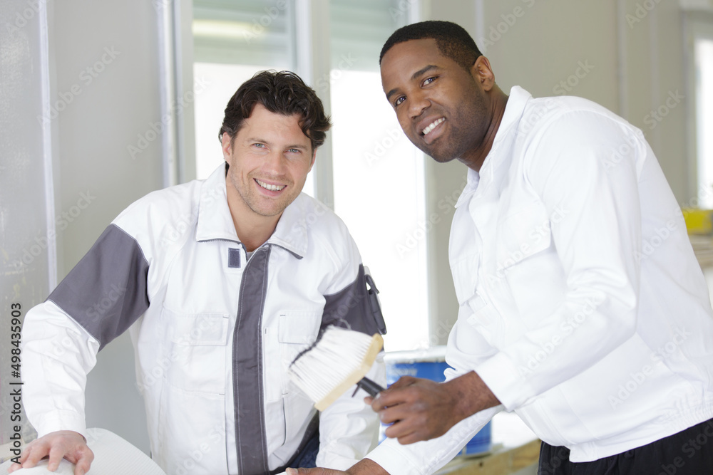 Obraz premium two male decorators applying wallpaper paste