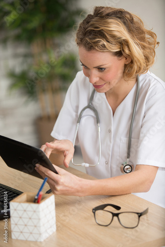 Quadro su tela female doctor sat at desk using a tablet