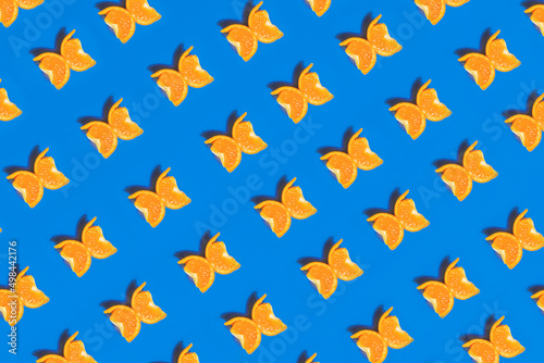 A colorful pattern made of tangerine slices looks like a butterfly on a blue background. 