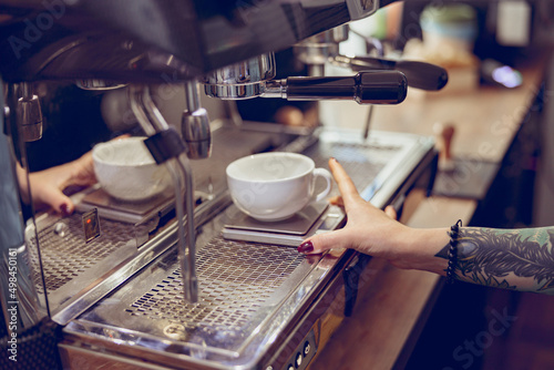 Female barista using professional coffee machine in coffeehouse