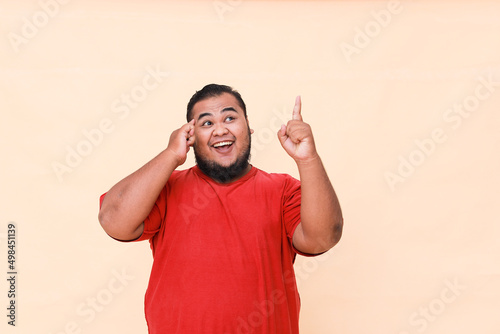 Shock Young asian man is surprised and shouting wow with pointing above with his hand isolated on cream background.