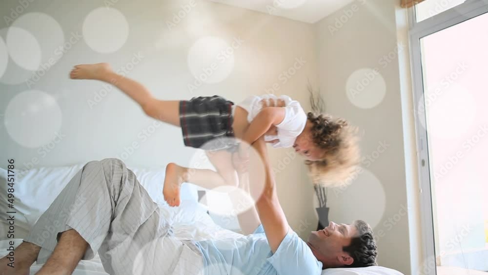 Animation of bokeh over happy caucasian father and son having fun at home Animation of bokeh over happy caucasian father and son having fun at home