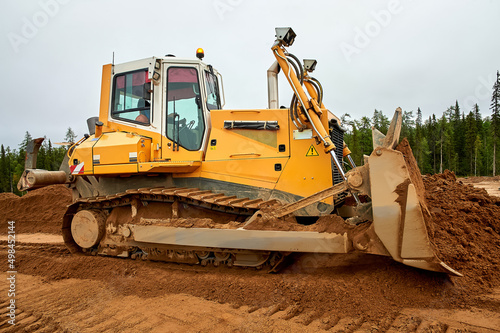 A yellow tractor levels the site with sand photo