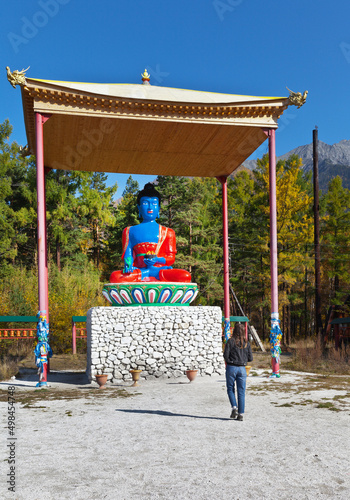 A tourist girl examines the sculpture of the Medical Buddha at the Arshan hydrotherapy resort photo