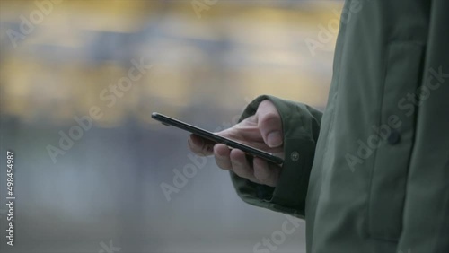 Close up of hands scrolling through a smartphone. Train station.
