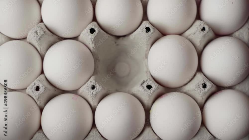 Hand picks up chicken eggs from a cardboard tray, top view Hand picks up chicken eggs from a cardboard tray, top view