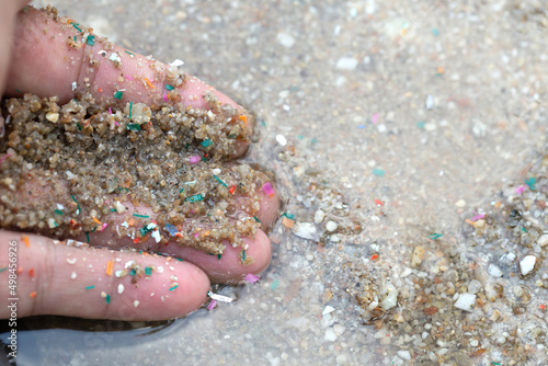 Close-up side shot of hands shows microplastic waste contaminated with the seaside sand. Microplastics are contaminated in the sea. Concept of water pollution and global warming. photo