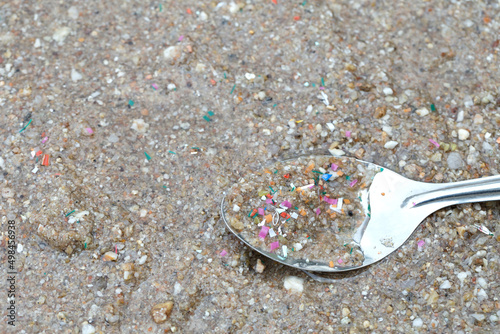 Environmental pollution and water microplastic. Microplastic with spoon in the seaside sand. Microplastics are contaminated in the sea. Microplastic problem.Threat to human health and the environment