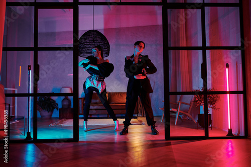 Tablou pe pânză Two dynamic teenagers in posh attire performing vogue dance in loft studio, apar