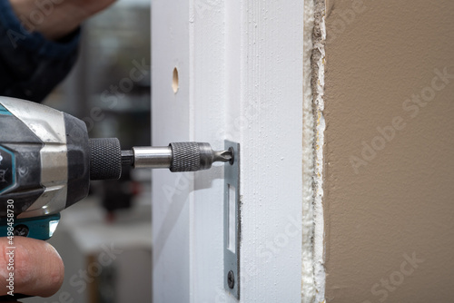 The carpenter installation the lock into the door with a drill