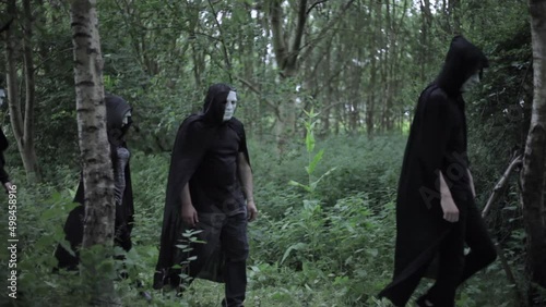 A cult of evil hooded druids are walking in the woods and about to perform a sacrifice ritual photo