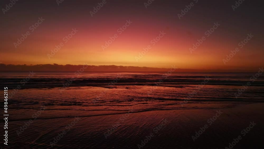 Early morning sunrise reflecting saturated colours across the waves on a deserted beach. Aerial view Early morning sunrise reflecting saturated colours across the waves on a deserted beach. Aerial view