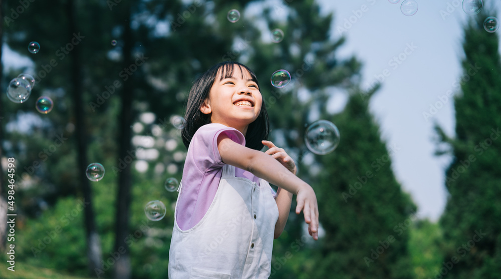 Image of Asian little girl playing with soap bubbles at park Image of Asian little girl playing with soap bubbles at park
