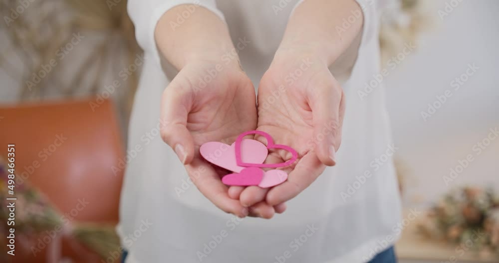Close up static shot of woman cupped hands showing pink paper hearts