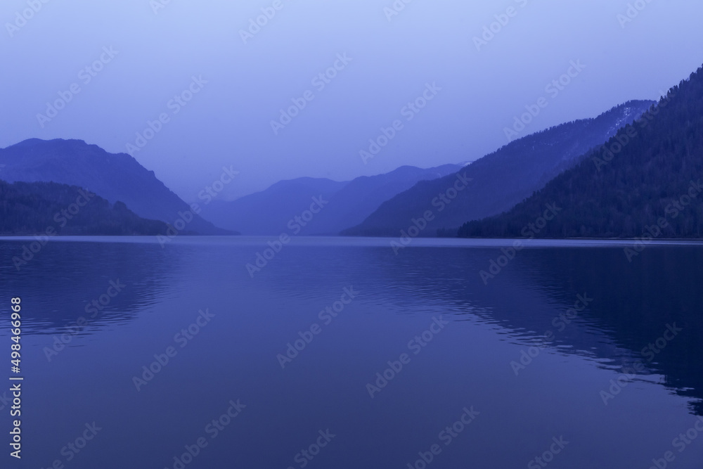 Lake Teletskoye, Altai Republic, Siberia, Russia. Blue clear sky and Mirror of lake. Abstract panoramic landscape, nature environment scene, monochrome background with tonal perspective