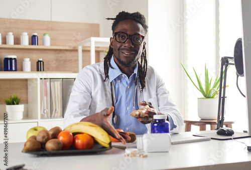 Afroamerican nutritionist looking at camera and showing healthy fruits in the consultation.